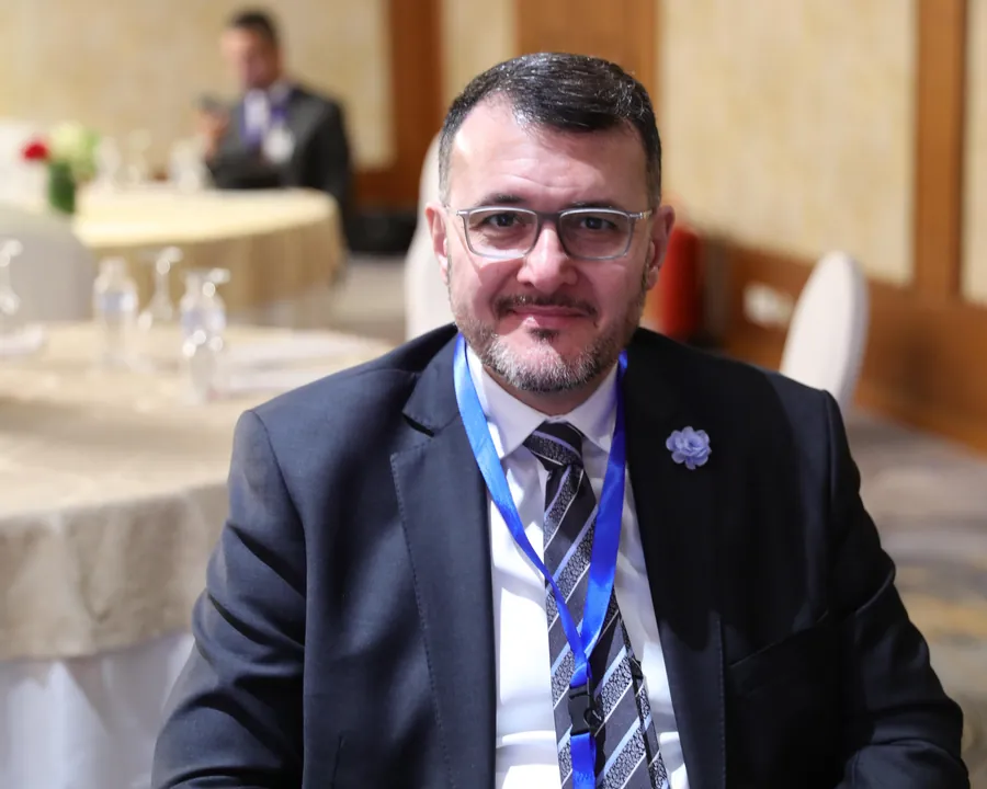 Dr. Nizar Baidoun smiling, seated at a conference